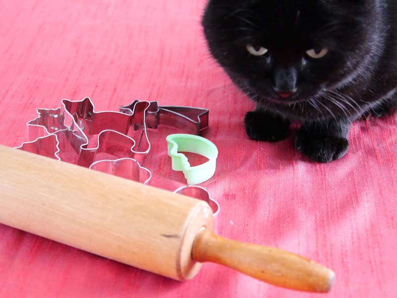 Katze und Keksausstecher beim Pltchenbacken